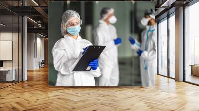 Healthcare worker health care workers wearing hazmat suits working together to control an outbreak of virus Wall mural